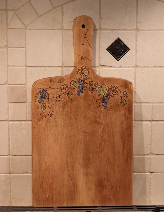 Woodburned grapes, grapevine and leaves on a maple charcuterie board